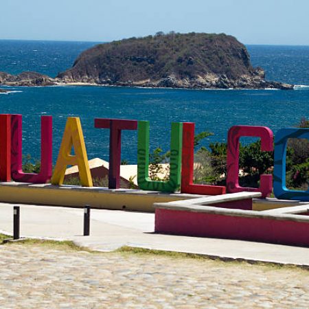 View of Tangolunda bay at Huatulco Oaxaca Mexico. La Montosa Island in the background and the word HUATULCO in concrete made letters.View of Tangolunda bay at Huatulco Oaxaca Mexico. La Montosa Island in the background and the letter O made of concrete in the main plain.
